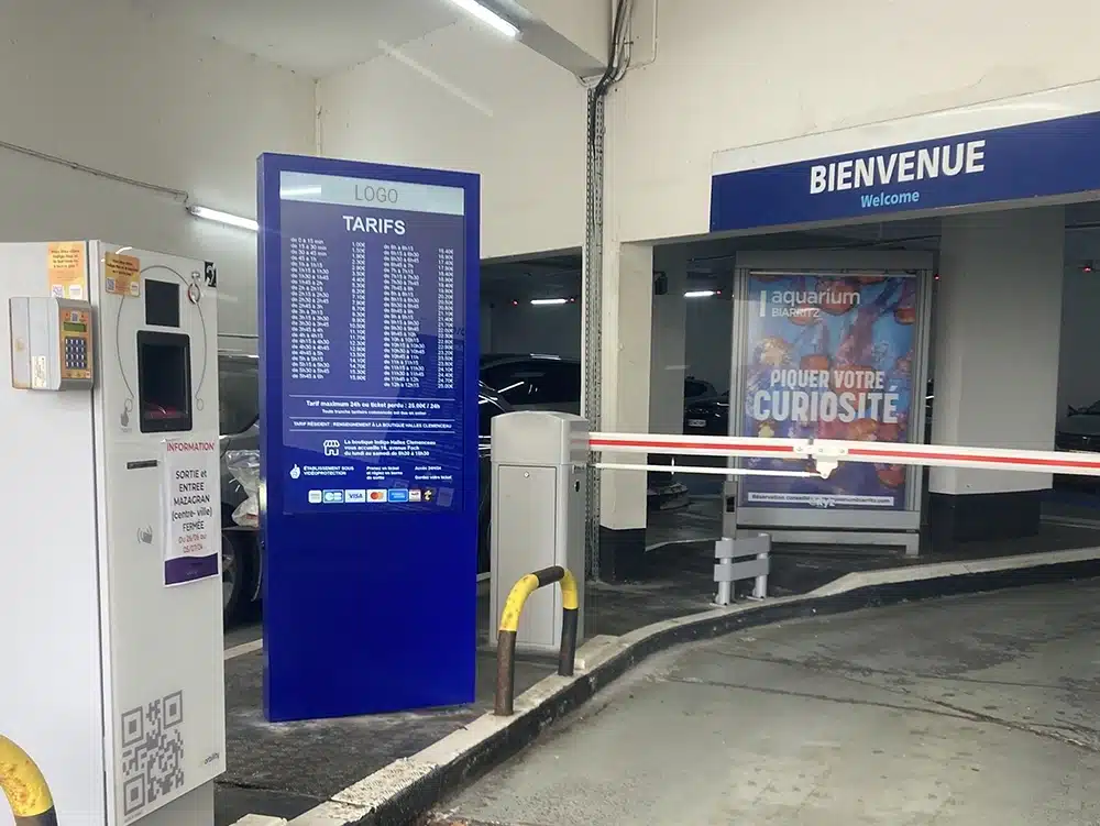 Totem vidéo intérieur affichant les tarifs à l'entrée d'un parking